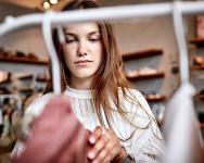 young female looking through clothing rack in a store